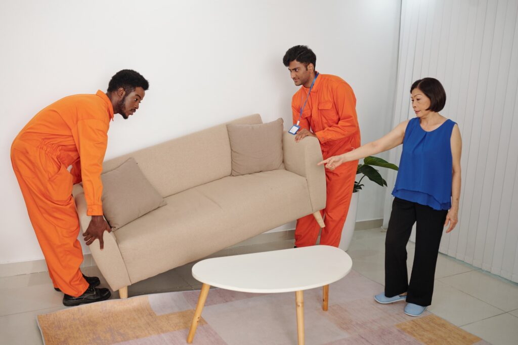 Asian woman showing place for sofa to movers